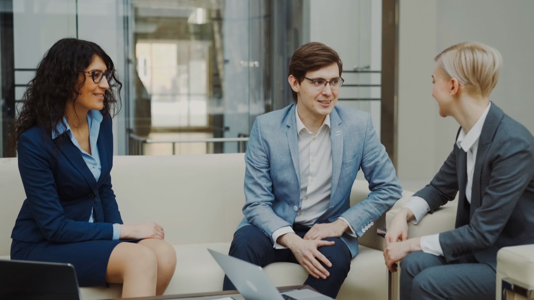 Three colleagues talking on a sofa in the office lounge